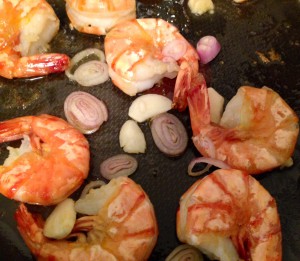 Wenn die Garnelen fast fertig sind, Knoblauch und Schalotten dazugeben