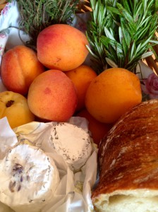Einkaufskorb mit Aprikosen, Ziegenkäse, Kräutern und Brot
